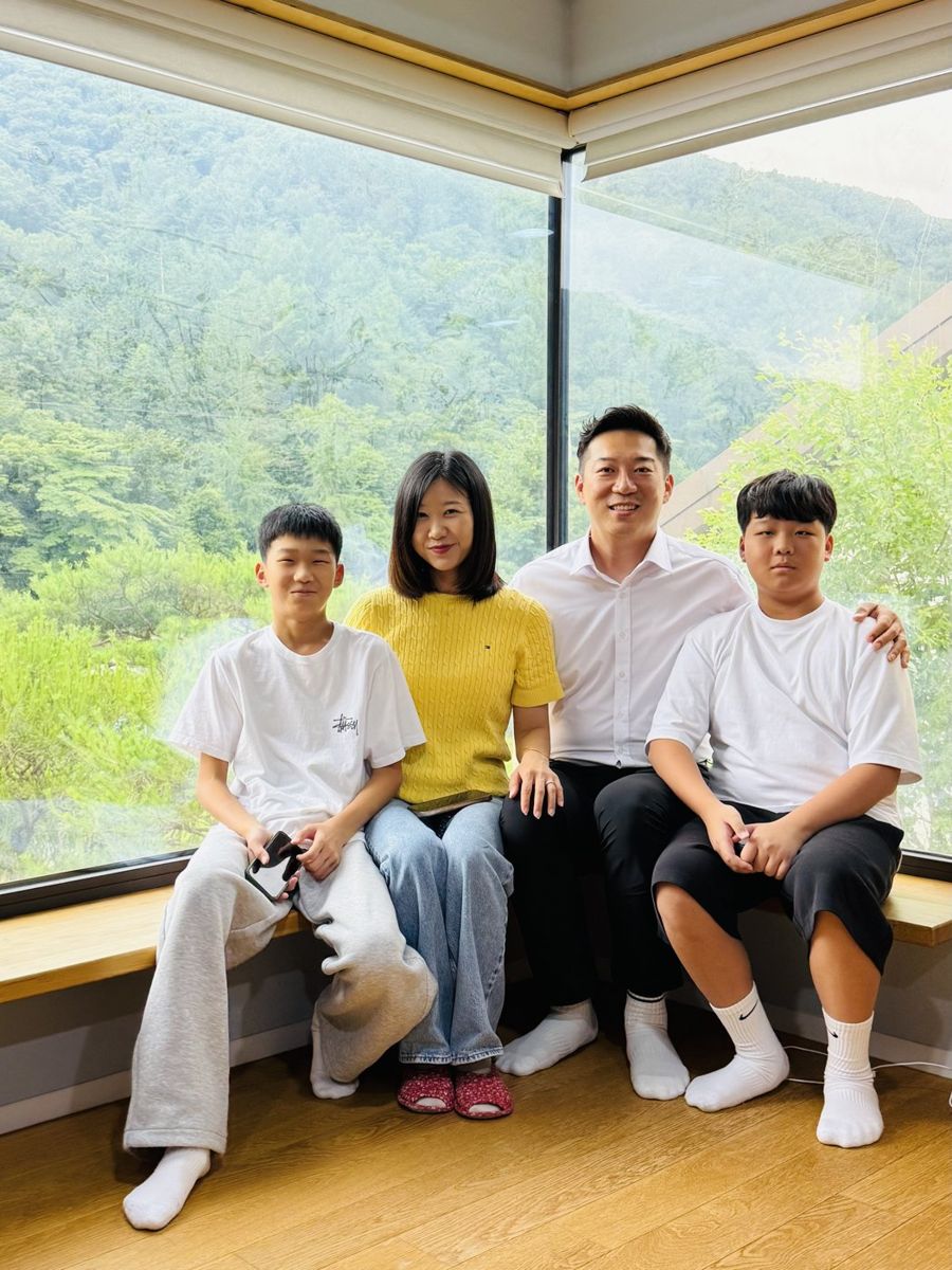 The Ji family sitting side by side on a bench by a window